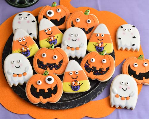 Jack o Lantern, Ghost and Candy Corn decorated cookies on displayed on a black plate.