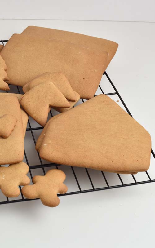 Baked gingerbread house cookies on a cooling rack.