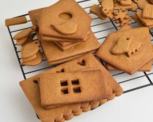 Baked and cooled gingerbread house panels layered on a cooling rack.