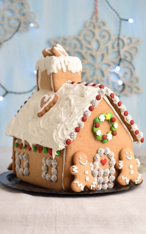 Assembled gingerbread house displayed on a black plate.