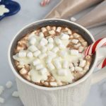 Mug filled with hot cocoa topped with chocolate snowflake and marshmallows.