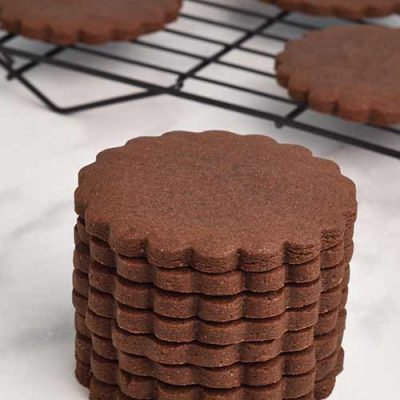 Baked scalloped edge cookies stacked on top of each other.