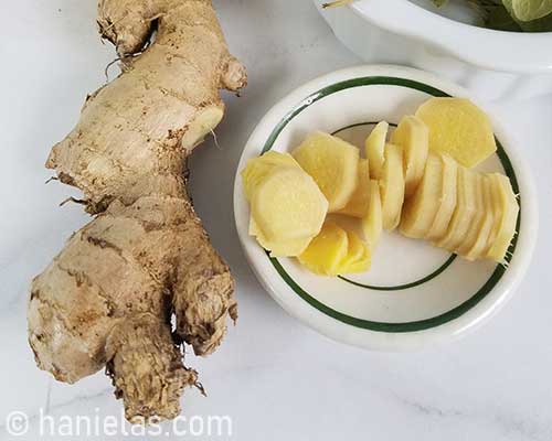 Peeled and sliced fresh ginger on a plate.