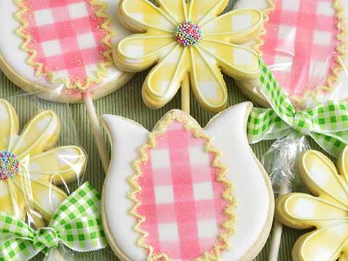 Decorated cookies on a stick arranged into a bouquet.