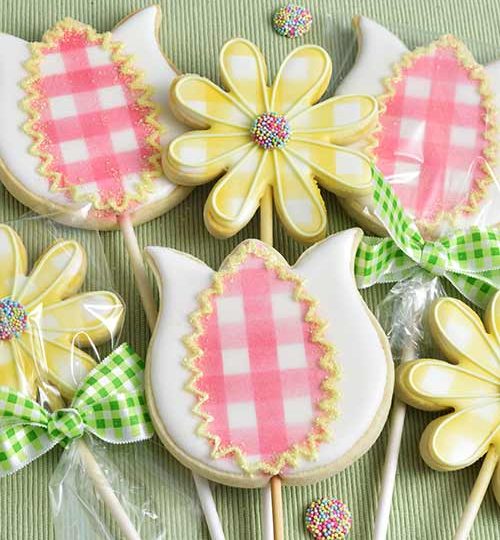 Decorated cookies on a stick arranged into a bouquet.