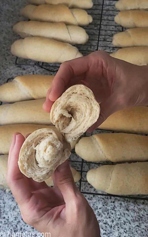 Hands holding a piece of torn bread.