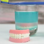 Jello denture in front of a drinking glass filled with jello.