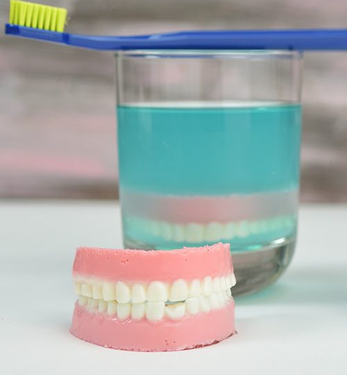 Jello denture in front of a drinking glass filled with jello.