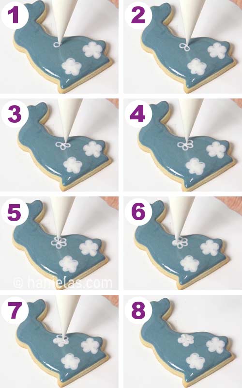 Piping wet on wet daisy flowers onto a freshly royal icing iced cookies.