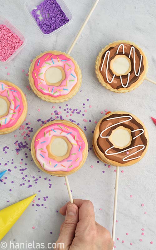 Hand holding decorated cookie pops.