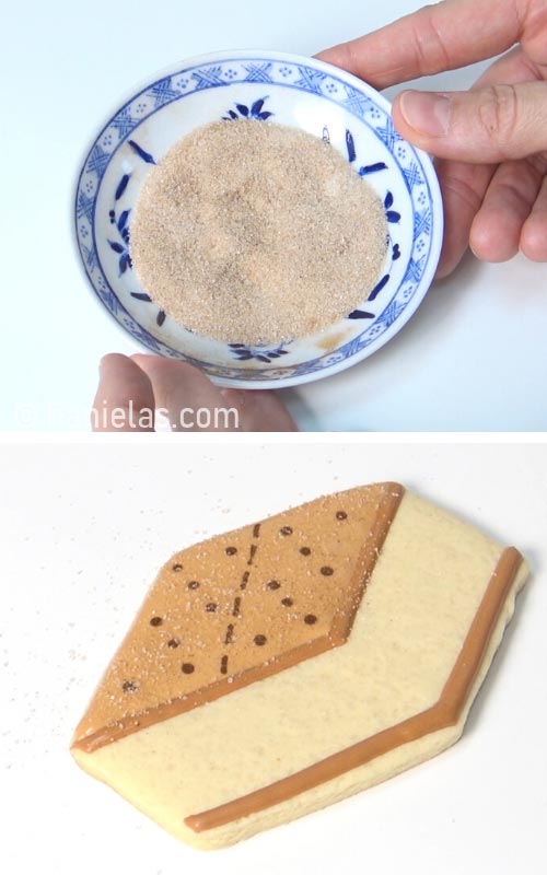 Dusting a freshly icing cookie with cinnamon sugar.