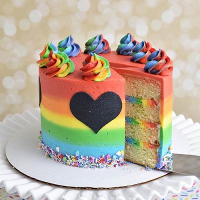 Decorated rainbow buttercream cake on a cake stand.