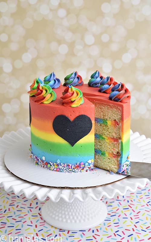 Decorated rainbow buttercream cake on a cake stand.