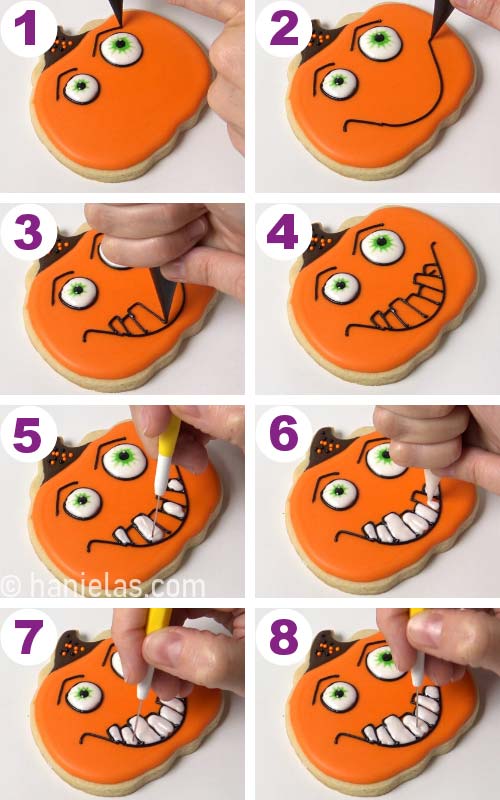Piping black eyebrows and white teeth onto a pumpkin shaped cookie.