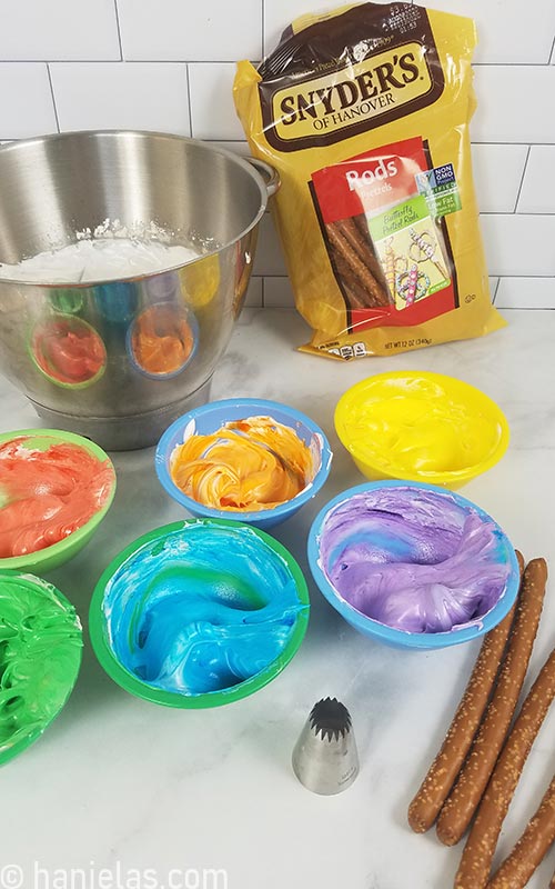 Colored meringue into small bowls on a counter.