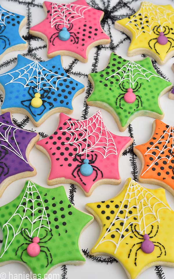 Spider web shaped decorated cookies with royal icing spiders and white spider web.