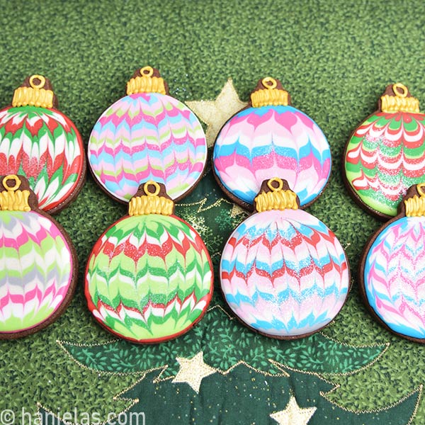 Chocolate cookies decorated with marbled royal icing on a pretty festive green background.