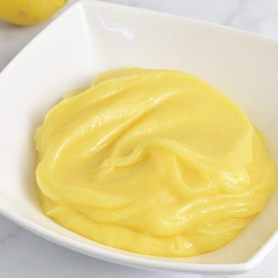 Yellow lemon curd in a white dish.