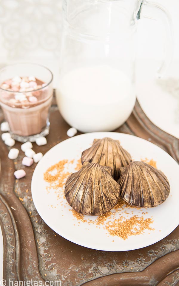 Molded chocolate seashells painted with edible gold paint plated on a white plate.