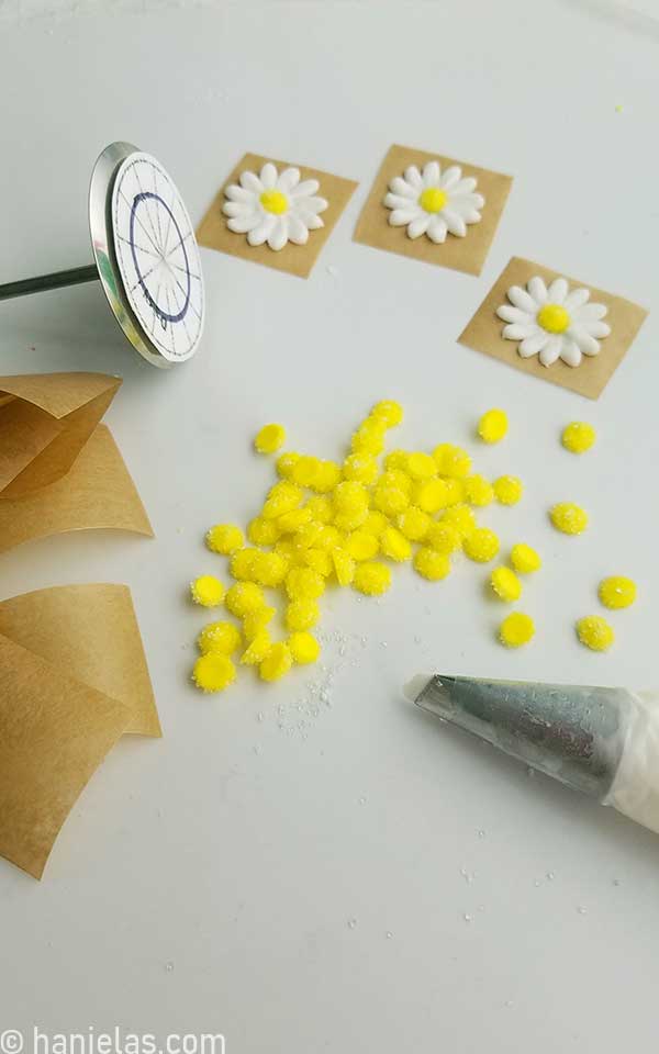 Royal icing yellow flower centers on a white surface.