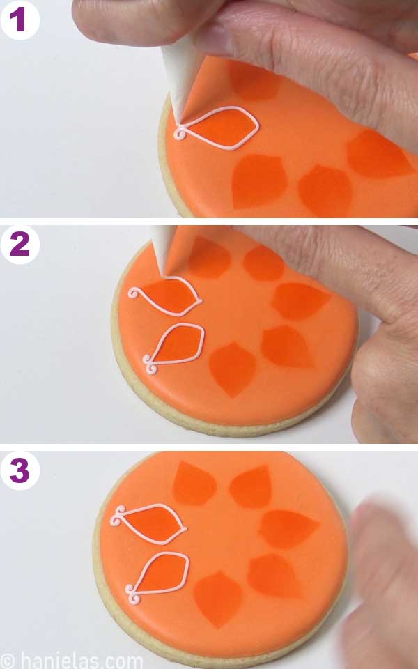 Piping white designs with royal icing orange iced cookie.