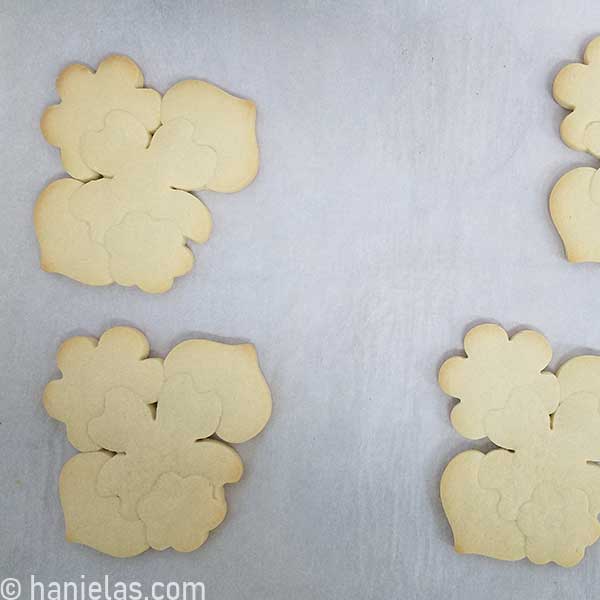  Baked cookies constructed from several cookie cutters on a parchment lined baking sheet.