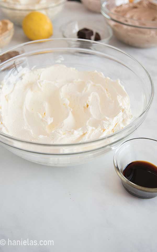 Vanilla buttercream in a glass bowl with a small glass bowl with Vanilla extract on a side.