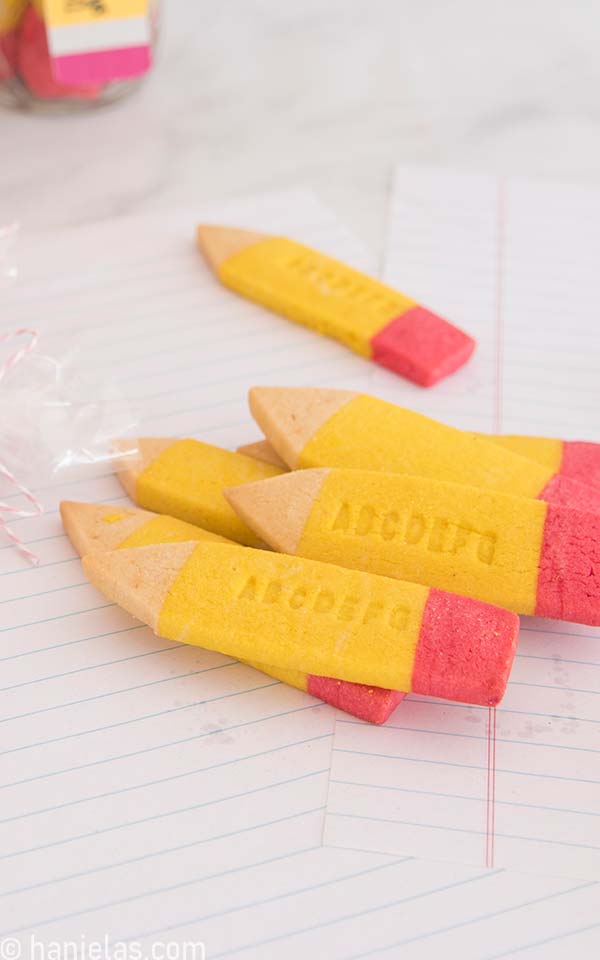 Baked yellow, pink, brown pencil cookies with alphabet impressions.