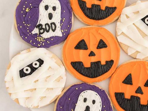 Round cookies decorated with orange, purple buttercream for Halloween.