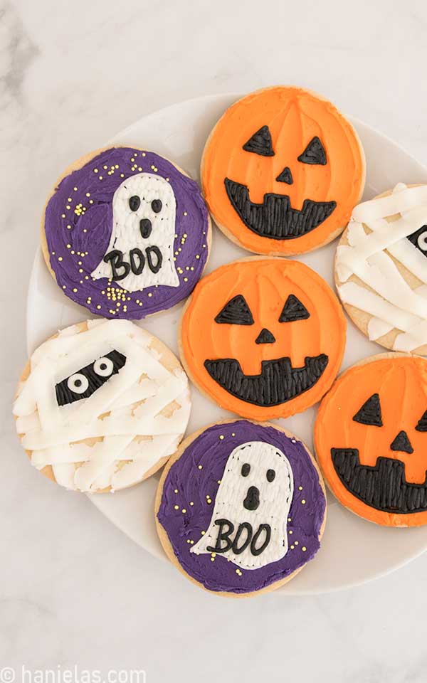 Round cookies decorated with orange, purple buttercream for Halloween.