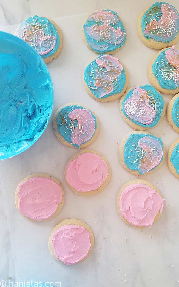 Buttercream frosted round cookies on a marble slab.
