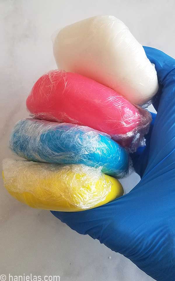 Hand holding fondant wrapped in food wrap.