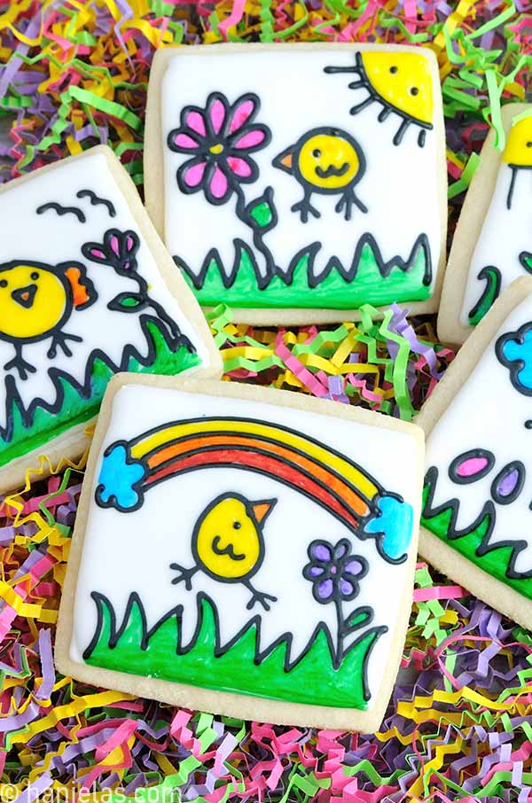 Square cookies decorated with white icing, with black outlined designs and colored with edible markers.