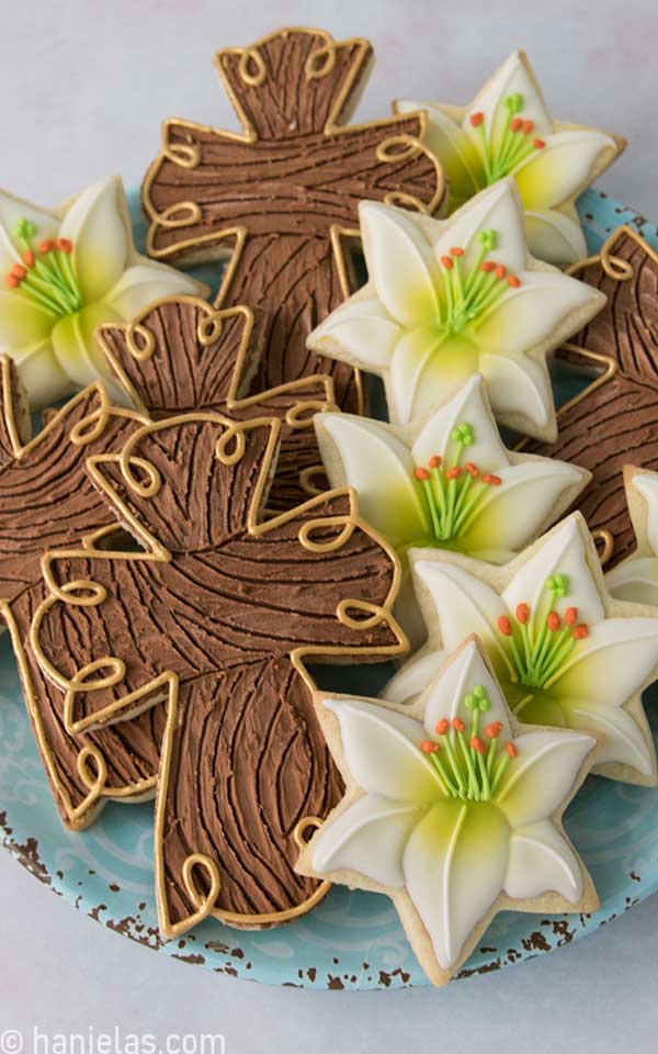 Decorated cross and lily flower cookies on a blue plate.