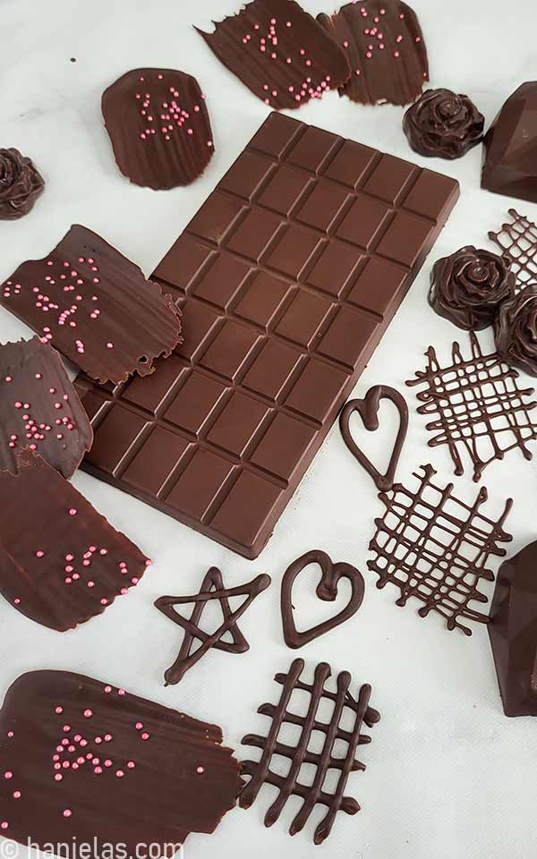 Different shaped of molded chocolate and piped chocolate decorations on a parchment paper.