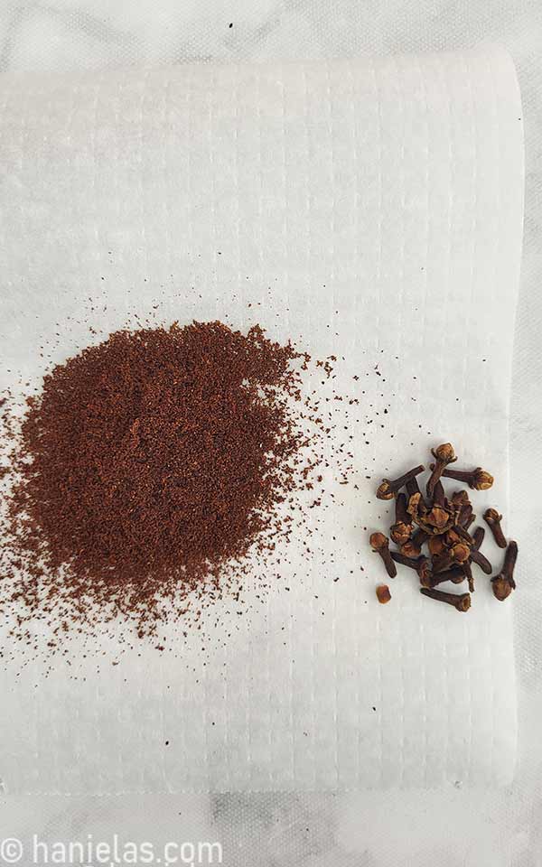 Ground and whole cloves on a parchment paper.