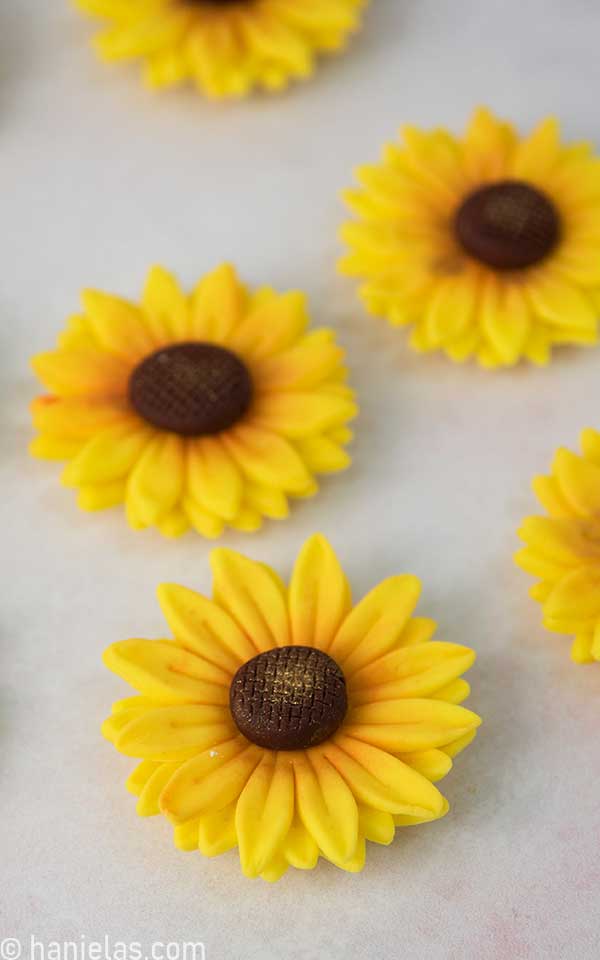 Several yellow fondant flowers on a light pink background.