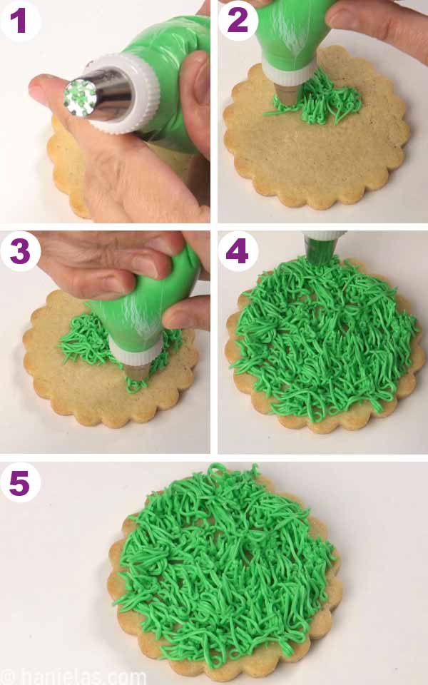 Hand holding a piping bag filled with green icing and fitted with grass piping tip.