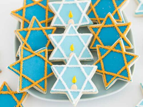 Nine decorated star cookies on a white round plate.