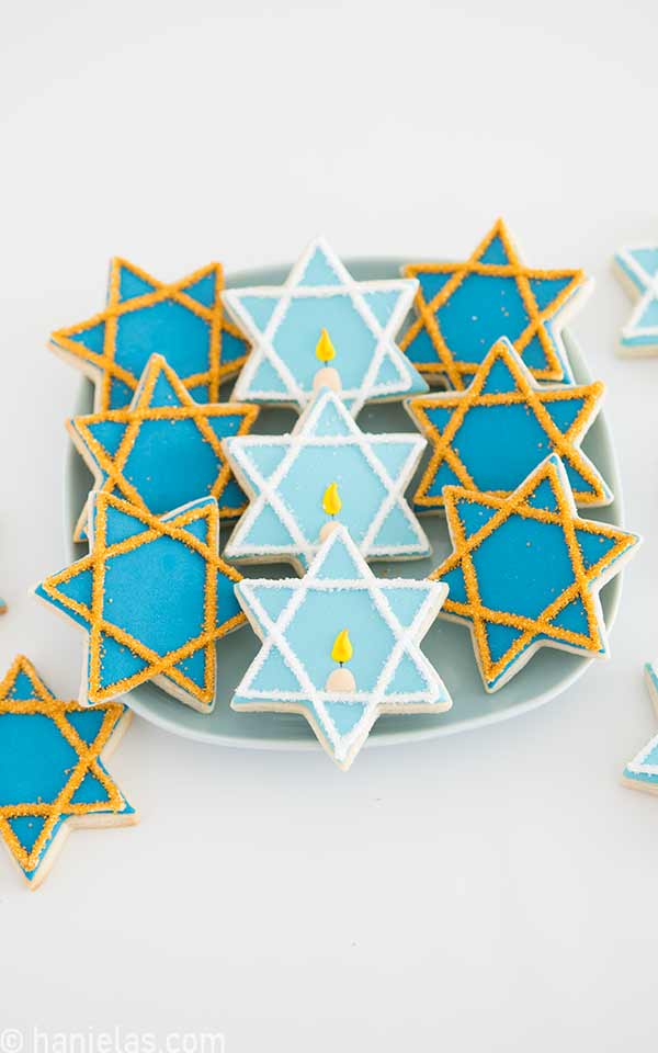 Nine decorated star cookies on a white round plate.