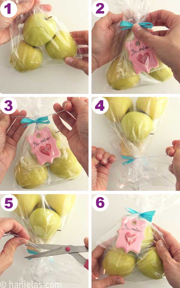 Apples in a clear bag with a pink cookie attached.