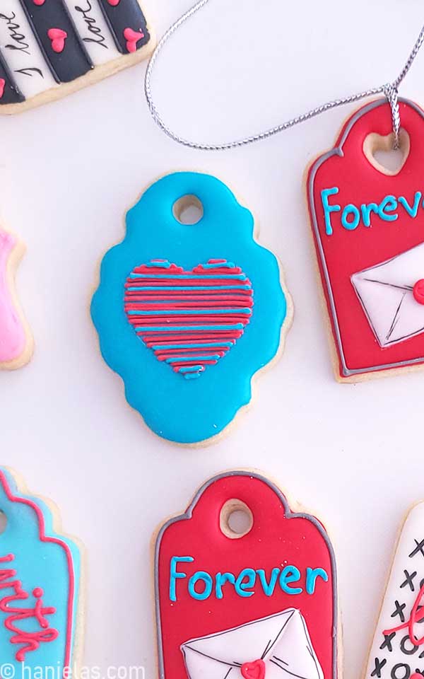 Teal colored plaque cookie with linear heart on the top.
