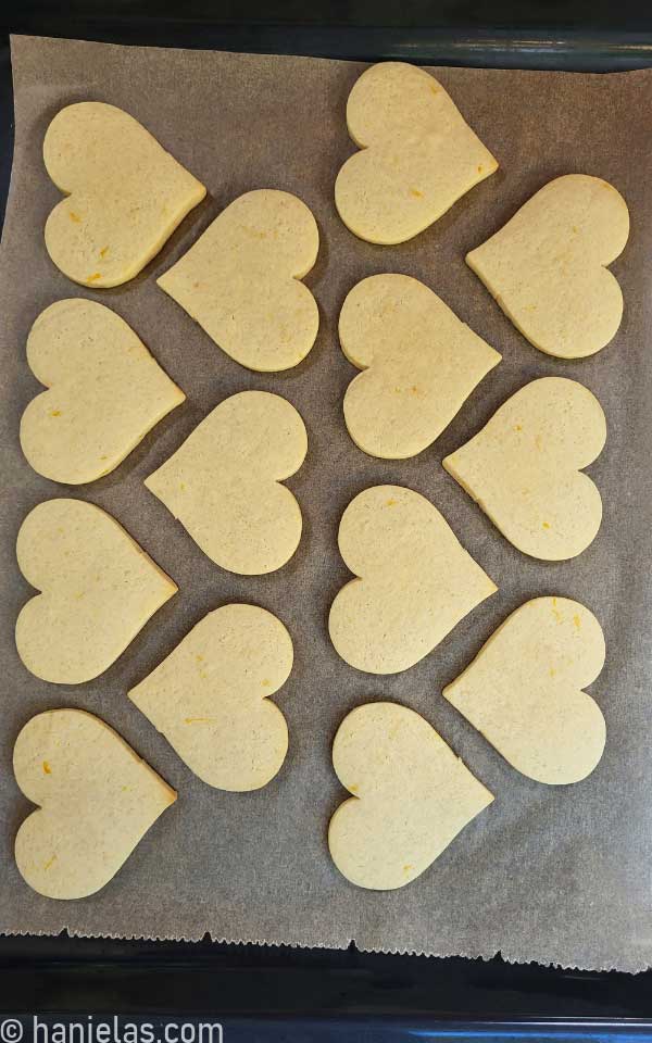 Baked cookies on a baking sheet lined with brown parchment.