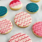 Close-up of a round cookie decorated with white and red icing.