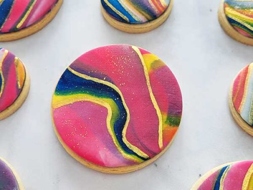 Close-up of cookies decorated with colorful icing and edible gold paint.