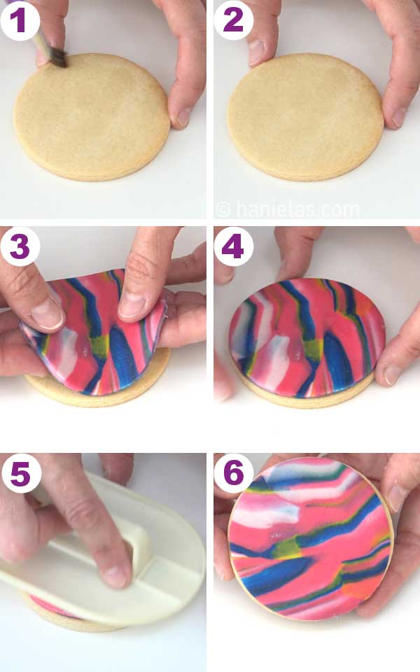 Fingers holding a piece of colored fondant, placing it onto a cookie.