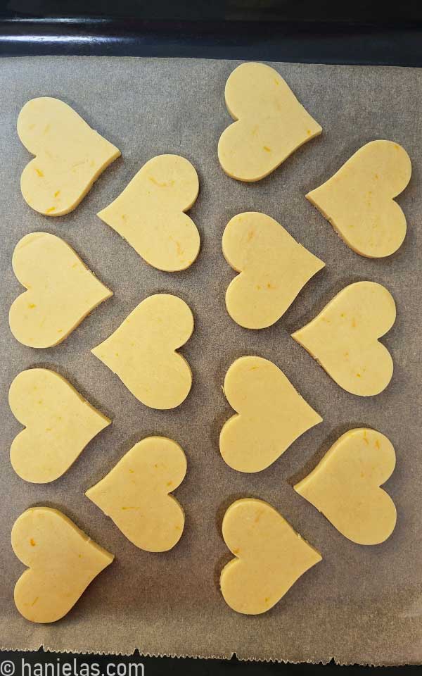 Raw cookie dough cut-outs on a baking sheet lined with parchment.