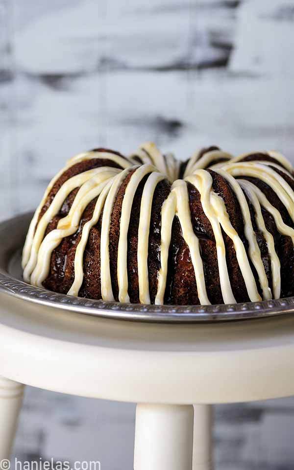 Bundt cake with a frosting drizzle on a silver tray.