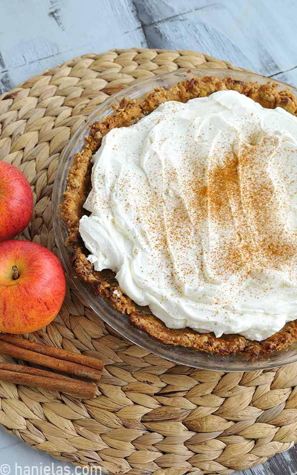 A glass pie dish with baked pie with whipped cream topping.