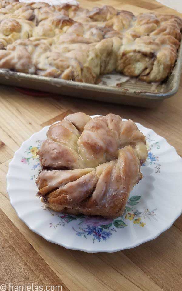 A twisted bun on a white plate with a floral design.